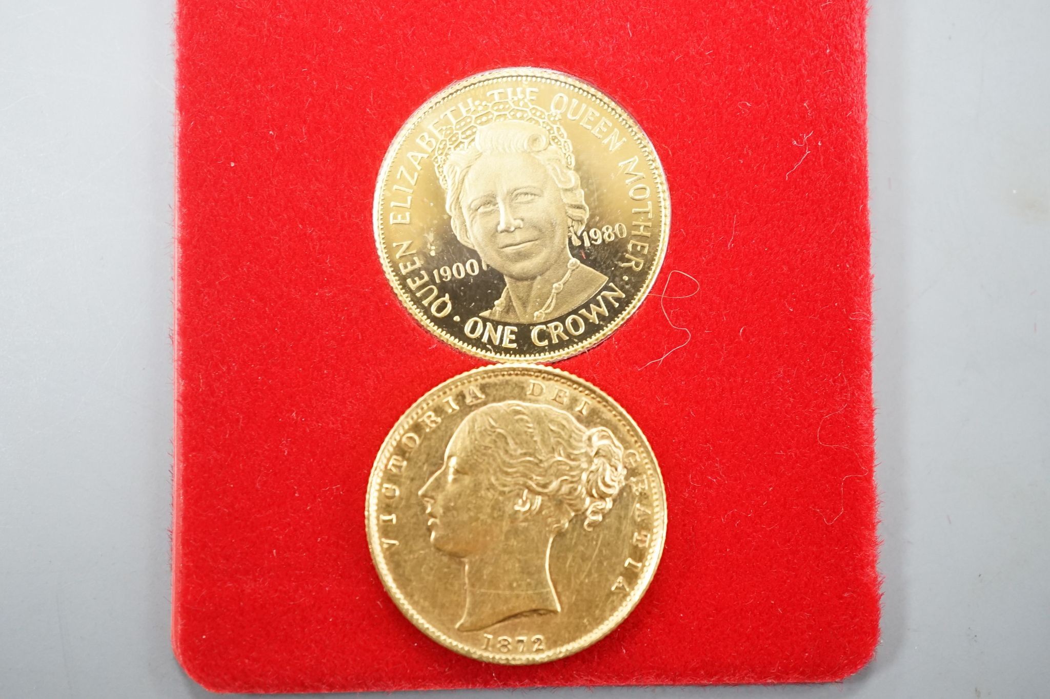 A Victoria 1872 gold sovereign and a Queen Mother 80th Birthday commemorative gold One Crown.